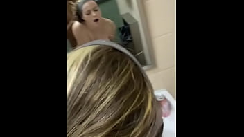 A beautiful young woman is bent over in a public restroom